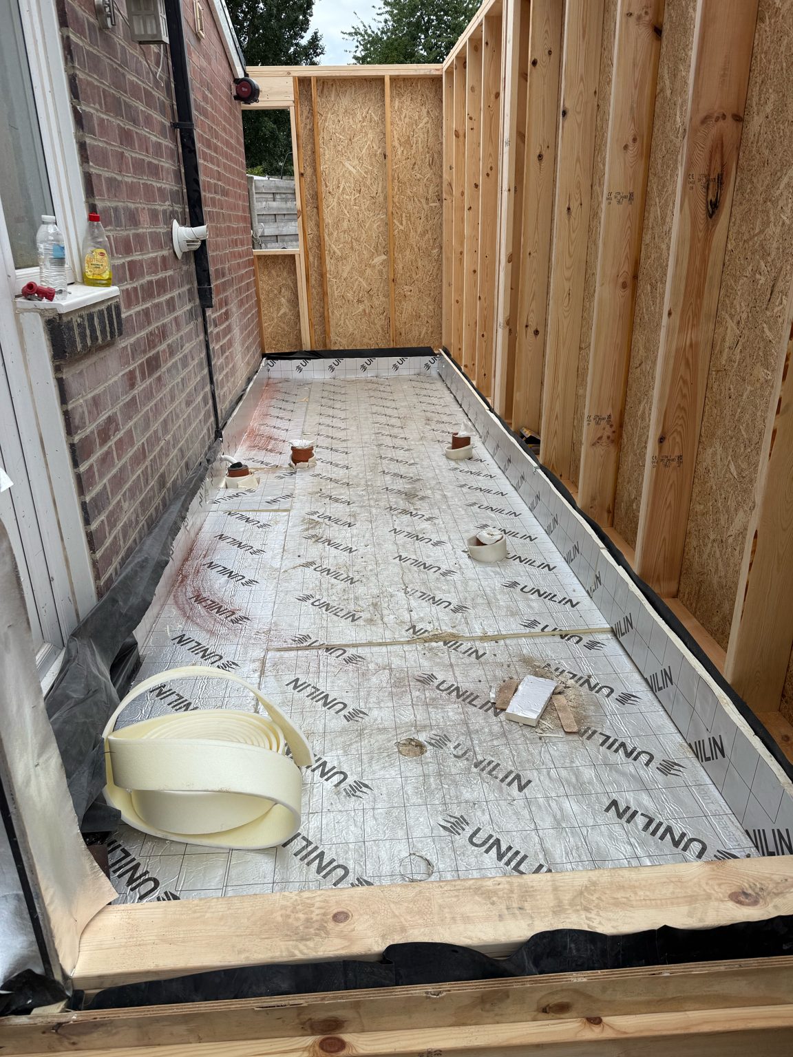 Timber frame walls with OSB sheathing and an insulated floor of insulation boards laid before screed, inside the Rothwell extension